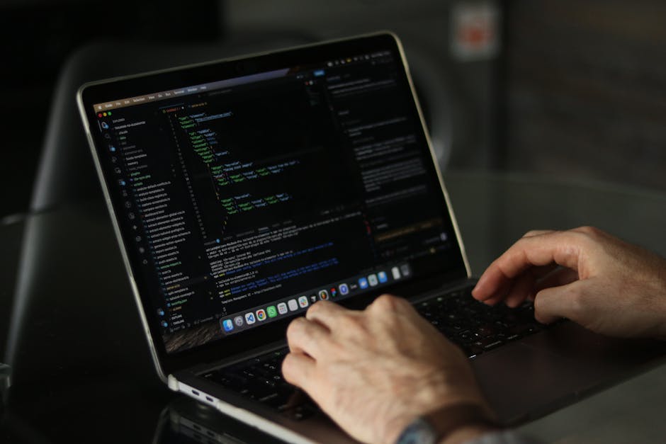 Close-up view of a laptop displaying a programming code editor on the left side of the screen, with a large graphic of a calculator on the right side, featuring orange buttons for operations and numbe